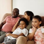 A joyful family of four enjoying time together on a comfy sofa indoors.